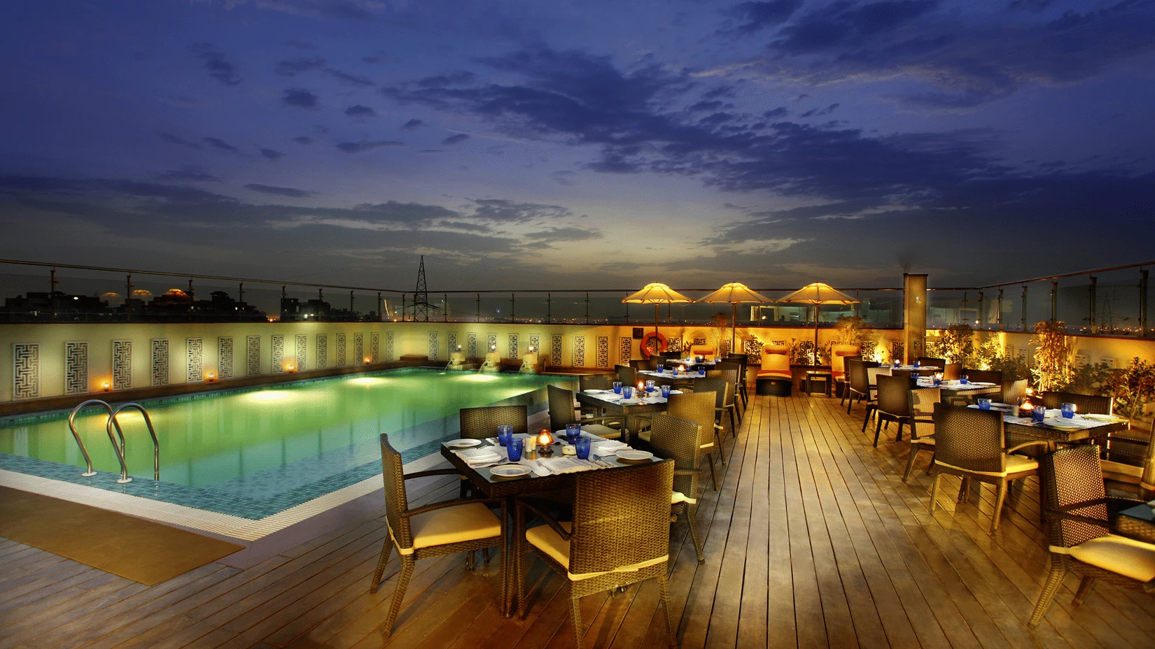 Mahagun Sarovar Portico Suites rooftop pool and terrace dining at dusk