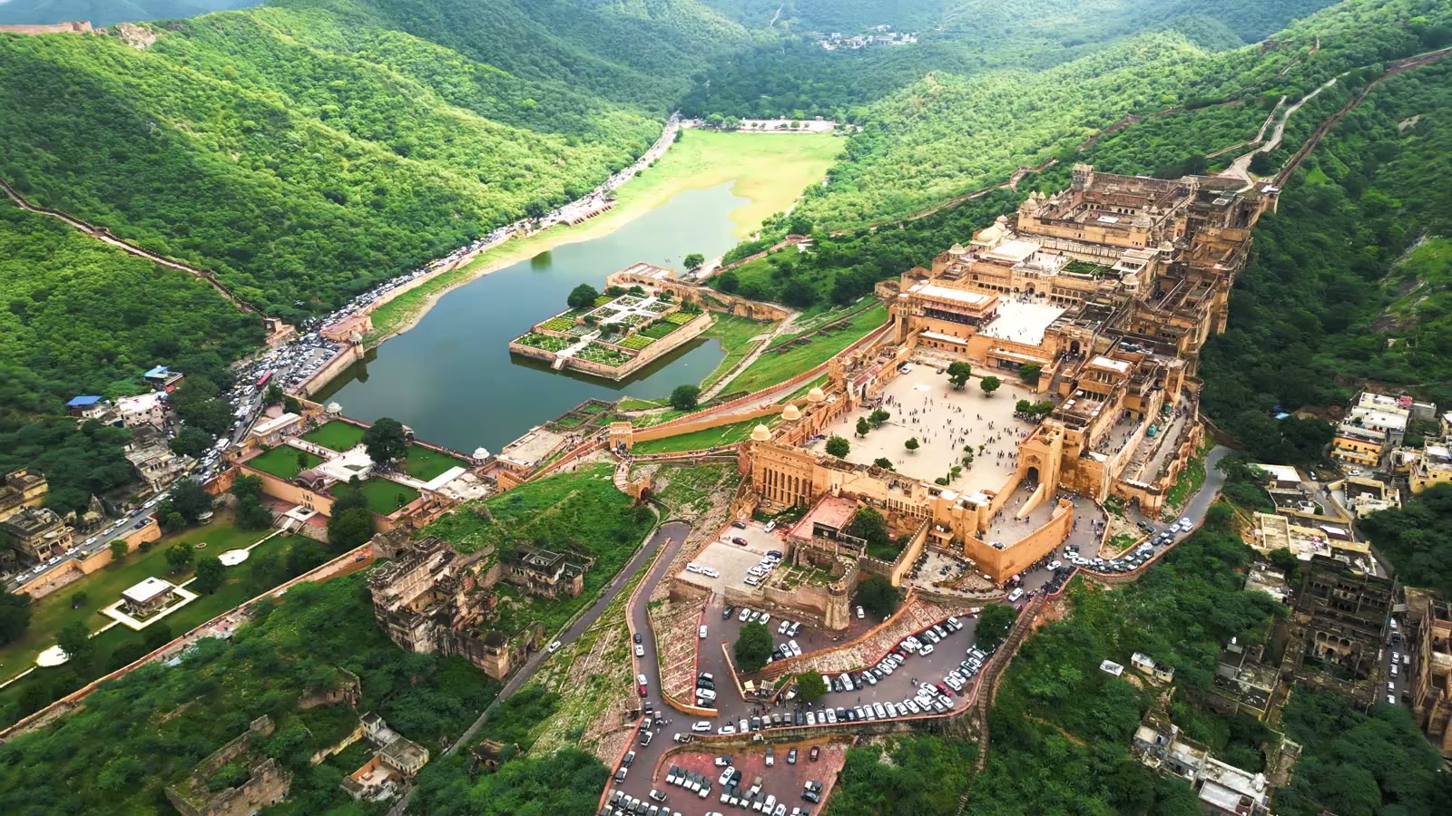 An aerial view of Amber Fort and Maota Lake among the green hills of Jaipur.