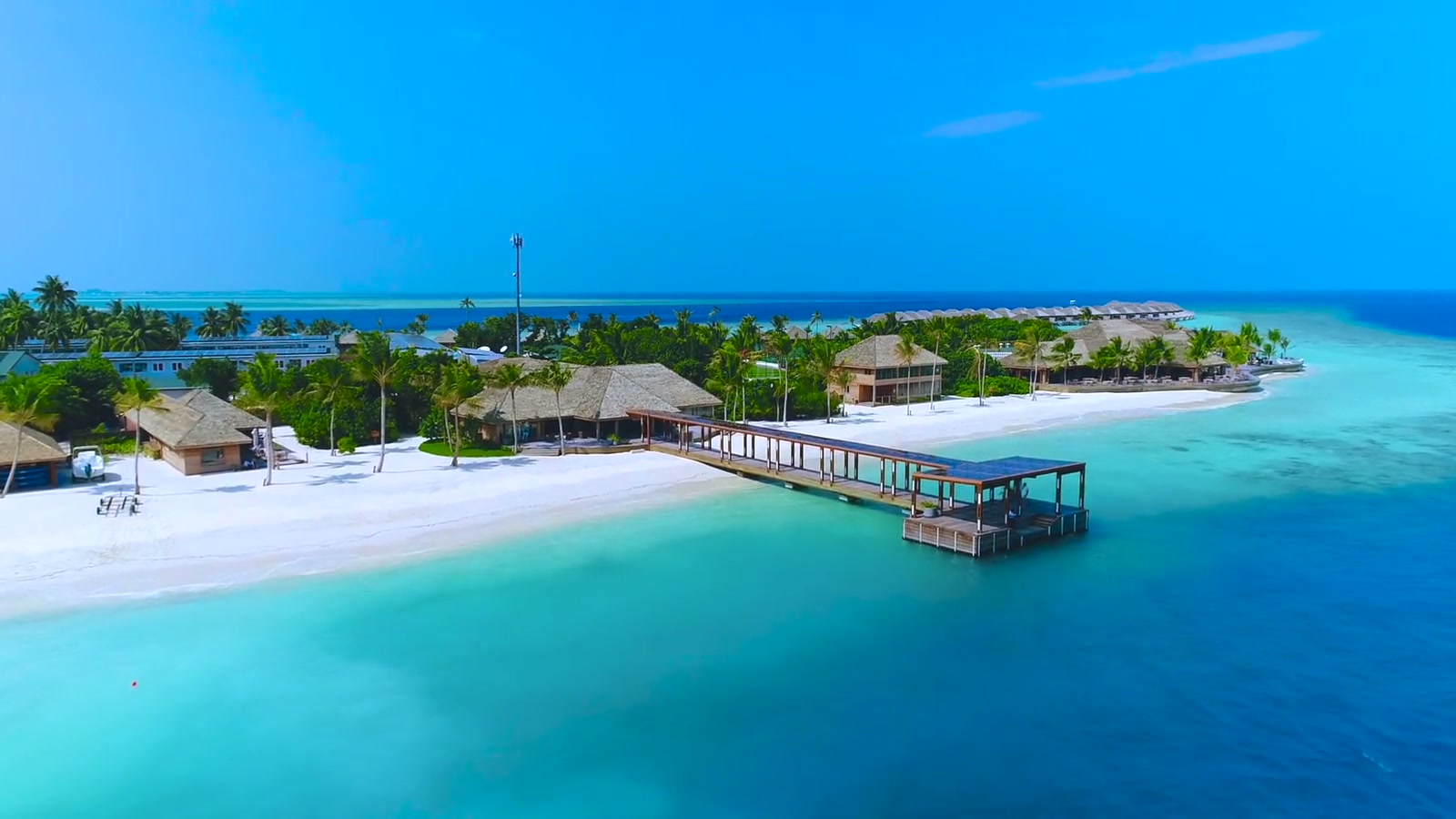 An aerial view across a Maldives island beach and turquoise lagoon