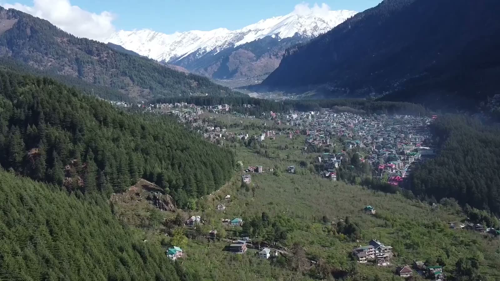 An aerial view over the Manali valley towards snow-capped Himalayan mountains.