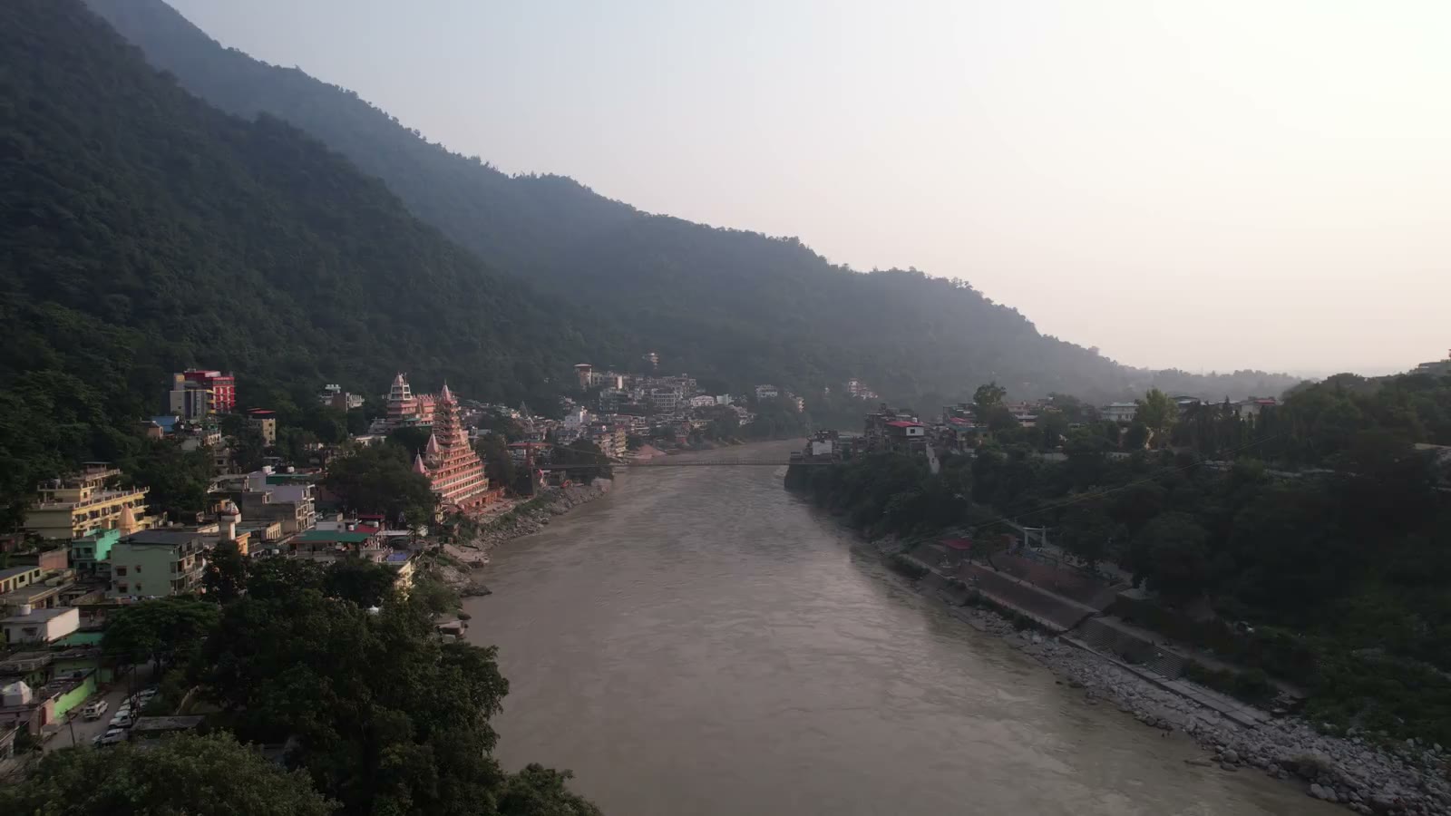An aerial view of the Ganga winding past temples and wooded hills in Rishikesh.