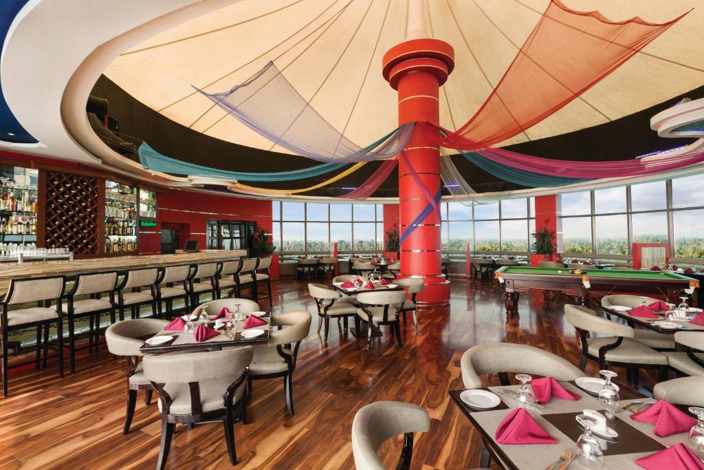 Dining and bar area with tables, pool tables and colourful ceiling drapes, shown on the Ramada Alleppey listing.