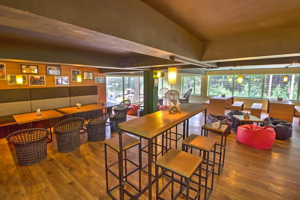 Restaurant seating with wooden tables and windows facing greenery.