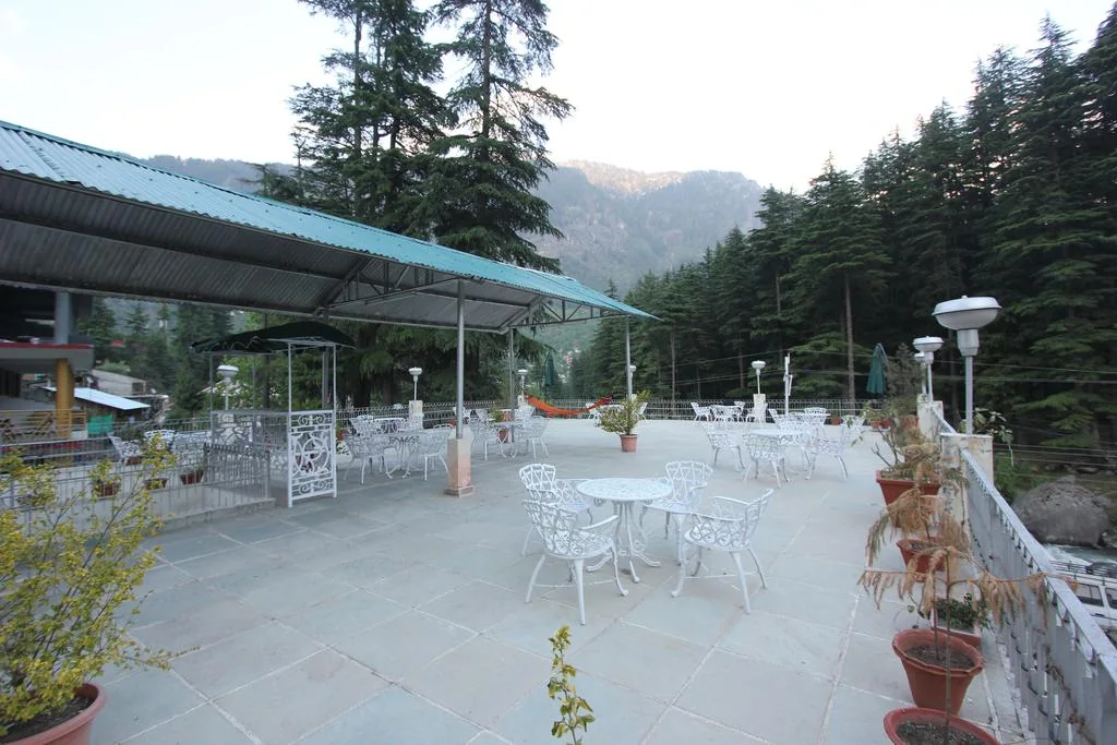 Open-air terrace seating framed by trees and mountain slopes.