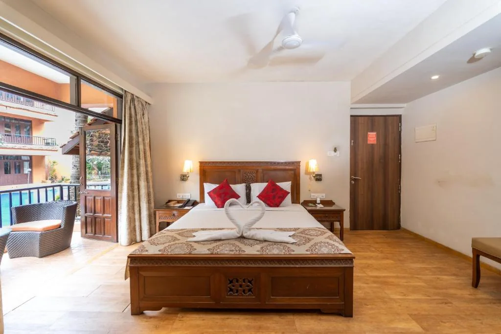 Guest room with a wooden bed, seating and open balcony doors.