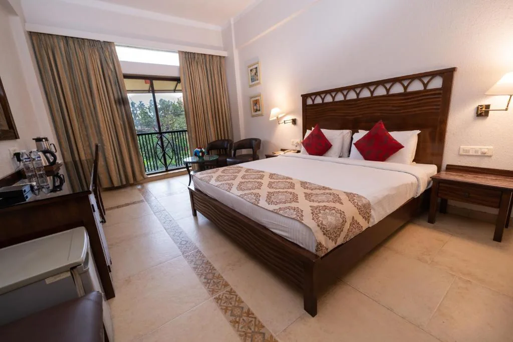 Double room with balcony doors, wooden furnishings and red accent cushions.