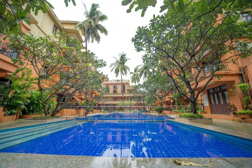 Blue swimming pool between palms and the hotel wings at Neelams The Grand.