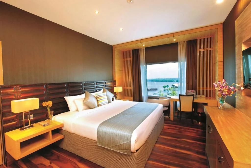 Warm-toned guest room with a desk and window overlooking the water.