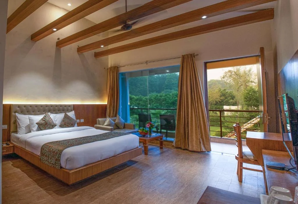Guest room with wood ceiling beams and balcony doors facing greenery.