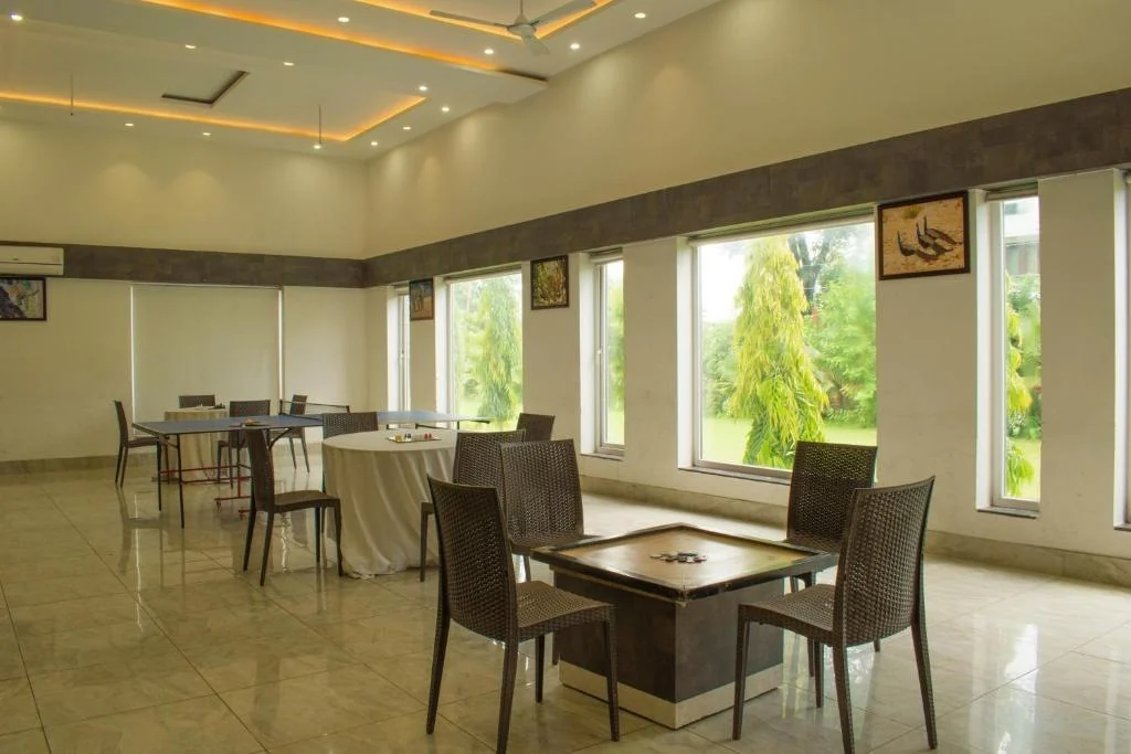 Resort restaurant tables beside large windows and greenery.