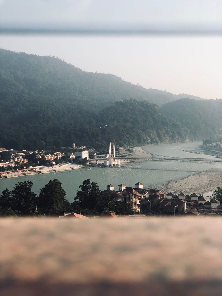 The Ganga and a suspension bridge beneath wooded hills in Rishikesh